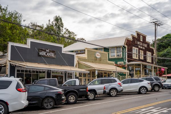 A street scene with parked cars in front of several buildings, including one with 